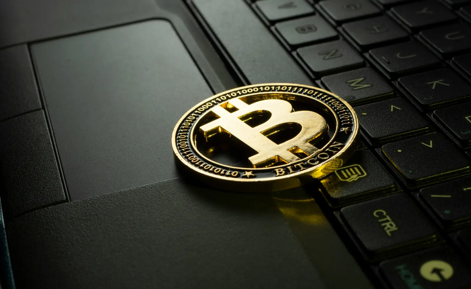 Goldene Bitcoin-Münze auf Laptop-Tastatur