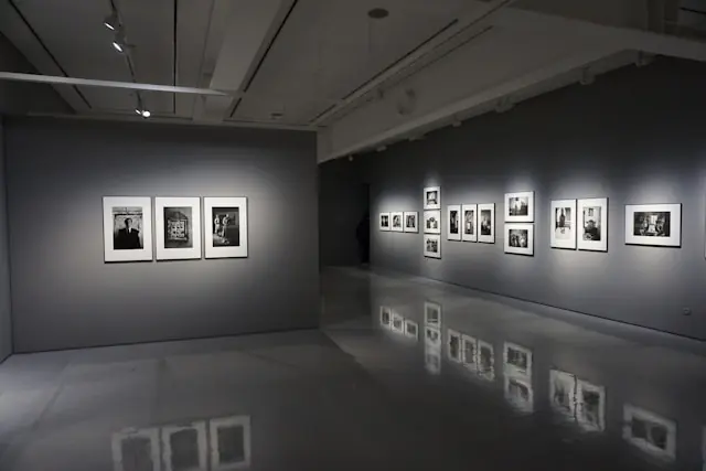 Gerahmte Schwarzweißfotografien an grauen Galeriewänden mit Spiegelung im Betonboden vor dem Hintergrund des ermäßigten Steuersatzes auf Kunstkäufe