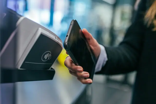 Hand hält ein Smartphone an ein Bezahlterminal mit Kontaktlos-Symbol als Bezug zum Kurssprung der Fintech-Aktie Sezzle