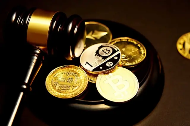Richterhammer neben goldenen Bitcoin-Münzen auf dunklem Untergrund als Bezug zur einjährigen Haltefrist für Kryptogewinne