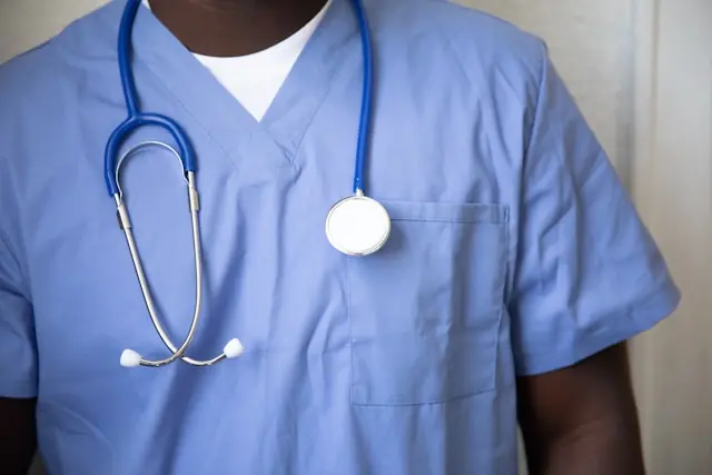 Person in blauer Klinikkleidung mit Stethoskop um den Hals im Zusammenhang mit dem Lizenzdeal zwischen HUTCHMED und GSK