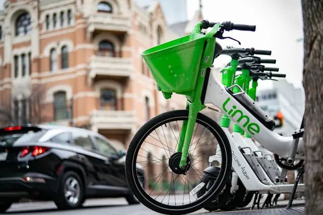 Reihe grün-weißer Lime-E-Bikes mit Firmenlogo am Straßenrand vor einem Backsteingebäude als Bezug zum Kurssprung der Lime-Aktie Richtung Rekordhoch