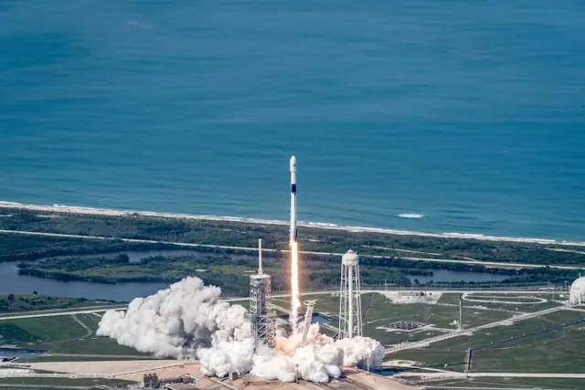 Falcon-9-Rakete beim Abheben von der Startrampe an der Küste mit weißer Abgaswolke als Bezug zum Kursrutsch der SpaceX-Aktie