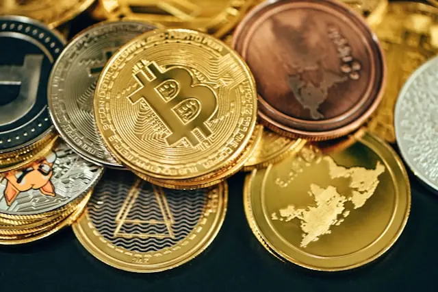 Mehrere physische Kryptomünzen mit Bitcoin im Vordergrund, passend zum geplanten Nasdaq-Börsengang von BGIN Blockchain, dem Hersteller hinter ICERIVER.