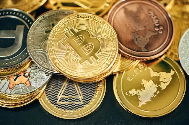Goldene Bitcoin-Münze obenauf zwischen weiteren Kryptomünzen in Gold, Silber und Kupfer als Bezug zum Kursgewinn von Twenty One Capital trotz anhaltender Krise