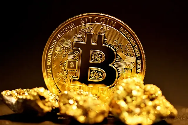 Goldene Bitcoin-Münze neben Goldnuggets Goldene Bitcoin-Münze neben Goldnuggets