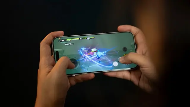 DarkIris IPO an der Nasdaq – Mobile-Game auf dem Smartphone Zwei Hände halten ein Smartphone im Querformat mit einem laufenden Mobile-Game als Bezug zum Nasdaq-Börsengang des Hongkonger Studios DarkIris.