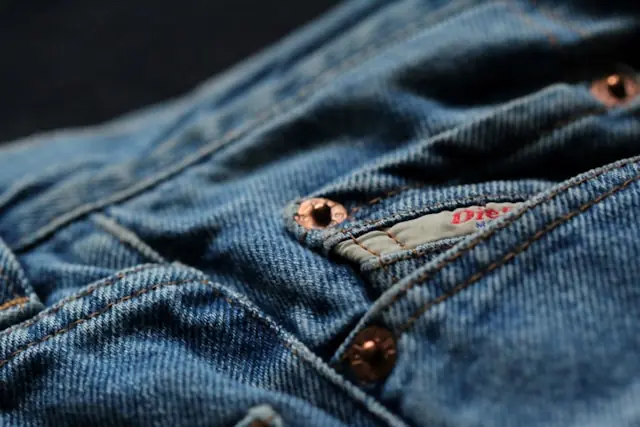 Vintage-Jeans als Sammelobjekt mit Nahaufnahme von Denim und Kupfernieten Nahaufnahme einer blauen Jeans mit Kupfernieten, Knopfleiste und rotem Markenetikett vor dem Hintergrund der Preise für Vintage-Jeans