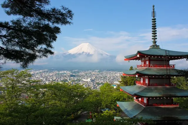 Japans Börse im Aufwind – Pagode vor dem Fuji und Stadtpanorama Japanische Pagode mit Blick auf eine Stadt und den schneebedeckten Fuji als Hintergrundbild zum Börsenaufschwung in Japan.