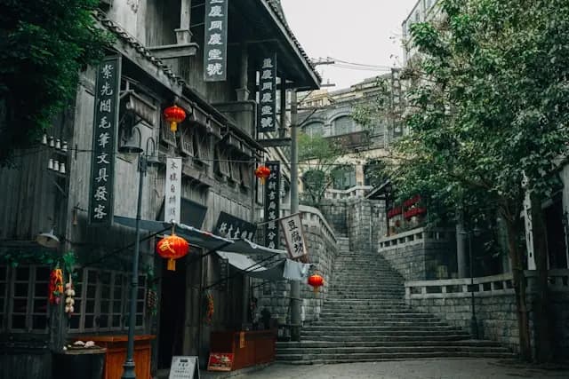 Maase-Aktie im Fokus – Altstadtgasse mit roten Laternen Gasse einer Altstadt mit roten Laternen und chinesischen Schriftzeichen auf Holzfassaden vor einer Steintreppe, ohne erkennbaren Bezug zur Maase-Aktie
