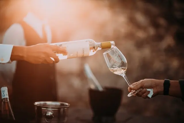 Burgund überholt Bordeaux mit eingeschenktem Weinglas im Sonnenlicht Ausschenken von hellem Wein aus einer Flasche in ein Glas vor unscharfem Abendlicht als Bezug zum Aufstieg von Burgund im Weinmarkt
