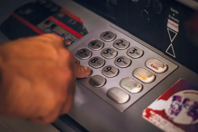 Avidbank Holdings Nasdaq-IPO – Geldautomat mit Zifferntastatur Eine Hand tippt eine PIN auf der Tastatur eines Geldautomaten, stellvertretend für das Bankgeschäft von Avidbank Holdings mit kleinen und mittleren Unternehmen in der Bay Area.