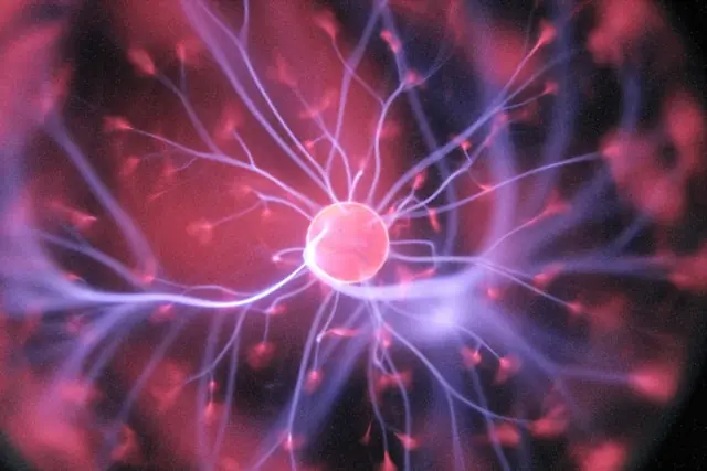Kurssprung bei X-Energy, Cathie Wood kauft – Plasmakugel mit Lichtbögen Leuchtende Plasmakugel mit rosa Kern und blau-violetten Lichtbögen als Bezug zum Kurssprung des Energieunternehmens X-Energy