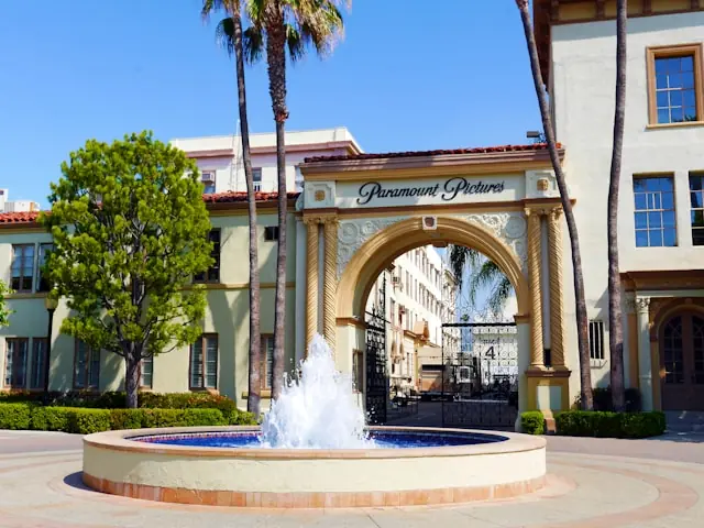 Paramount übernimmt Warner Bros – Eingangstor des Studiogeländes Historisches Eingangstor mit Schriftzug Paramount Pictures, Palmen und Springbrunnen als Bezug zur Übernahme von Warner Bros