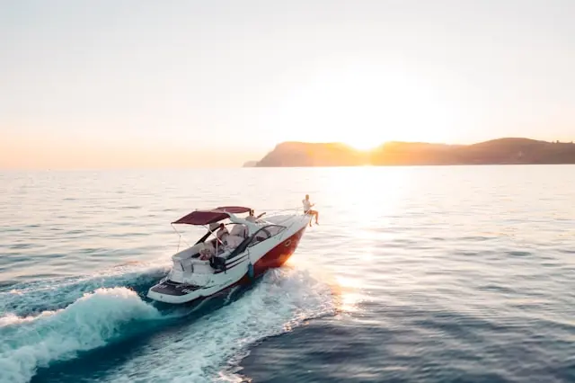 Twin Vee Powercats springt nach Grönland-Deal – Motorboot bei Sonnenuntergang Weißes Motorboot mit Personen an Bord auf offener See bei Sonnenuntergang als Bezug zum Kurssprung von Twin Vee Powercats