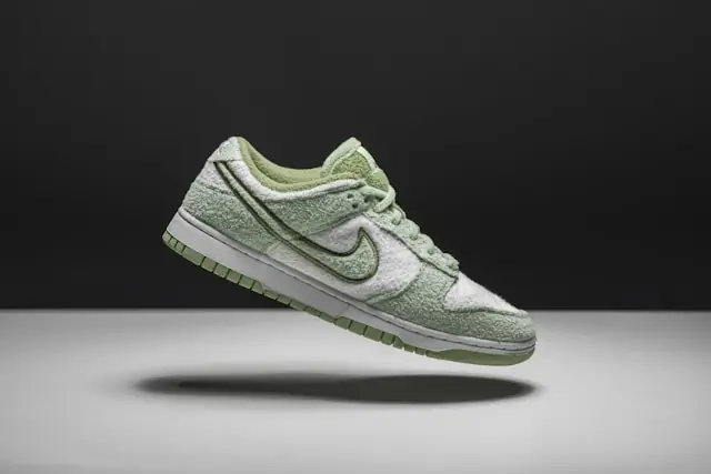 Verkaufsgebühren im Sneaker-Resale mit freigestelltem Sneaker Freigestellter grün-weißer Sneaker mit Frotteeoberfläche vor dunklem Hintergrund im Zusammenhang mit gestaffelten Verkaufsgebühren im Sneaker-Resale