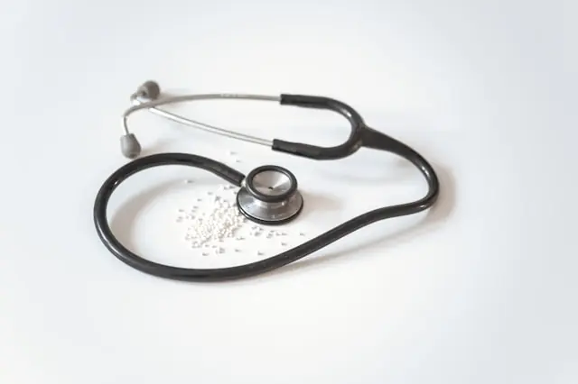 Oscar Health im Aufwind – Stethoskop mit Tabletten auf weißem Grund Schwarzes Stethoskop und kleine weiße Tabletten auf weißem Untergrund als Bezug zum US-Krankenversicherer Oscar Health nach dem Kursprung durch Wells-Fargo-Hochstufung.