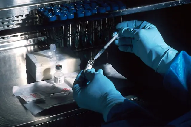 SL Science bricht nach Börsendebüt ein – Laborarbeit mit Spritze Behandschuhte Hände ziehen mit einer Spritze Flüssigkeit aus einem Fläschchen, im Hintergrund Probenständer, als Bezug zum Biotech-Wert SL Science