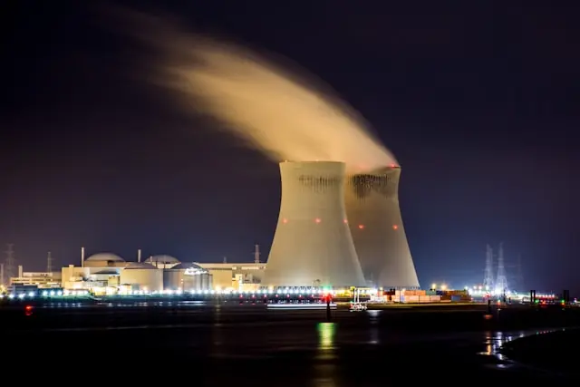X-Energy nach Börsengang unter Druck – Kernkraftwerk bei Nacht Zwei beleuchtete Kühltürme eines Kernkraftwerks bei Nacht mit aufsteigendem Wasserdampf, im Kontext des schwachen Börsendebüts von X-Energy