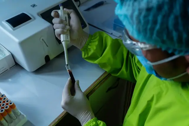 Caris Life Sciences IPO – Labormitarbeiter pipettiert Blutprobe Labormitarbeiter in Schutzausrüstung pipettiert eine Blutprobe im Rahmen molekulardiagnostischer Analysen, wie sie Caris Life Sciences für seinen Nasdaq-Börsengang bewirbt