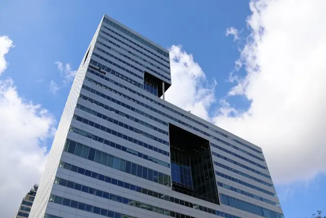 Accenture vor den Q3-Zahlen – Glasfassade eines modernen Büroturms Moderner Büroturm mit Glasfassade aus der Froschperspektive vor blauem Himmel, im Kontext der anstehenden Quartalszahlen von Accenture