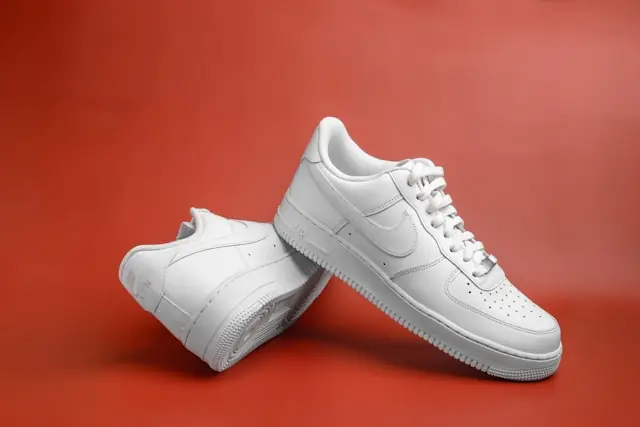 On Holding bricht ein mit weißen Sneakern vor rotem Hintergrund in Paar weiße Sneaker vor rotem Hintergrund als Bezug zum Kurseinbruch bei On Holding, Adidas und Puma