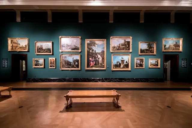 Artprice100 als Kunstmarktindex mit Gemäldehängung im Museumssaal Dicht gehängte Ölgemälde in Goldrahmen an dunkelgrüner Museumswand im Zusammenhang mit dem Kunstmarktindex Artprice100