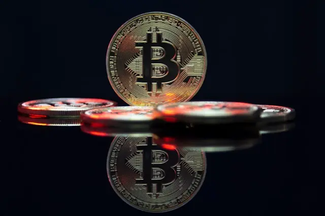 Circle Aktie klettert über 100 Dollar mit Bitcoin-Münzen als Kryptomotiv Goldene Bitcoin-Münzen mit Spiegelung auf dunkler Oberfläche als Bezug zum Kursanstieg der Circle-Aktie