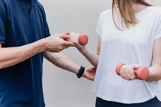 Hinge Health IPO an der NYSE – Physiotherapie mit Hanteln Zwei Personen beim Training mit roten Hanteln als Bezug zum NYSE-Börsengang des digitalen Physiotherapie-Anbieters Hinge Health