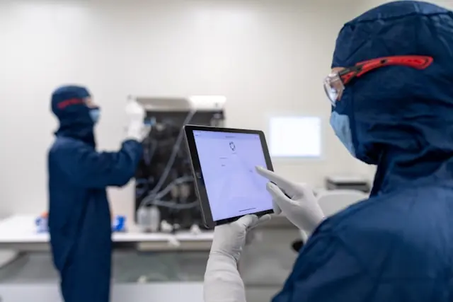 Iovance-Aktie klettert 12,5 Prozent mit Laborszene im Reinraum Zwei Mitarbeiter in blauen Schutzanzügen mit Tablet und Laborgerät in einem Reinraum als Bezug zum Kursanstieg der Iovance-Aktie
