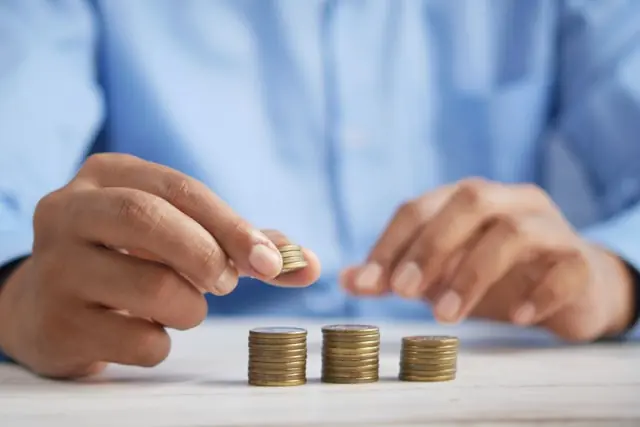 CoastalSouth Bancshares IPO – Hände stapeln Münzen auf Tisch Hände stapeln Münzreihen auf einem Tisch als Bezug zum Börsengang von CoastalSouth Bancshares und dem Wechsel von OTCQX zur NYSE