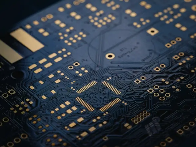 Broadcom-Aktie unter Druck – Nahaufnahme einer Halbleiterplatine Nahaufnahme einer blauen Leiterplatte mit goldenen Leiterbahnen und Chips als Bezug zum Kursrückgang bei Broadcom trotz Rekordergebnissen.