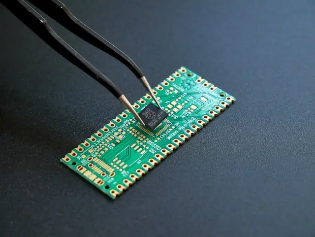 Comeback-Versuch der Halbleiteraktie AXT – Mikrochip auf Platine Pinzette an einem Mikrochip auf einer grünen Platine als Bezug zum Kurs-Comeback von AXT nach wochenlangem Ausverkauf