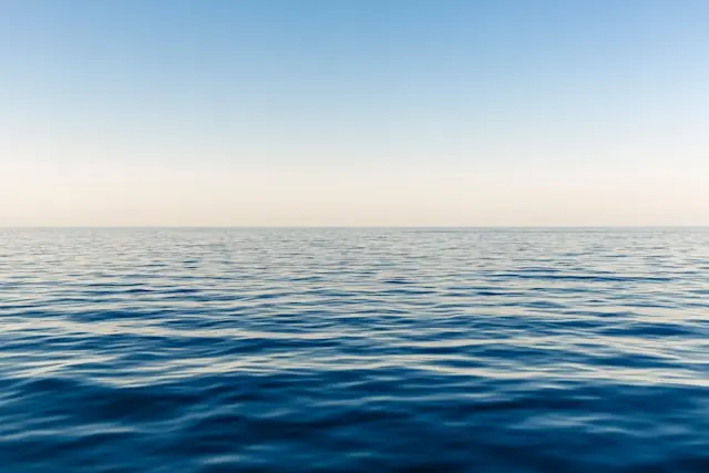 Deep-Sea-Aktien an der Börse – ruhige Meeresoberfläche am Horizont Ruhige Meeresoberfläche mit Horizont unter klarem Himmel als Bezug zum Anlagethema Deep-Sea-Aktien an der Börse