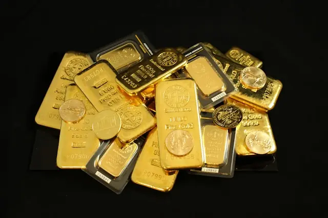 Gold stürzt trotz Krieg ab – gestapelte Goldbarren und Münzen Gestapelte Goldbarren und Goldmünzen auf schwarzem Hintergrund mit Bezug zum fallenden Goldpreis trotz anhaltender Kriegslage